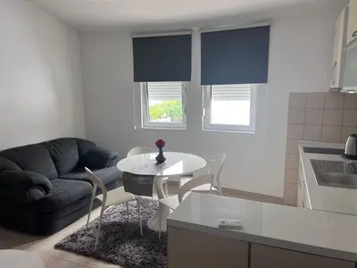 a living room with a couch and a table with chairs at ApartsDobraVoda in Dobra Voda