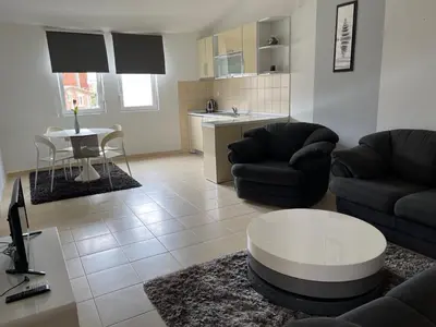 a living room with two couches and a table and a kitchen at ApartsDobraVoda in Dobra Voda