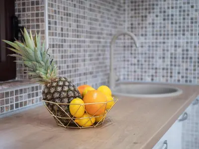 a pineapple and oranges in a bowl on a kitchen counter at Oscar Exclusive Apartment in Budva