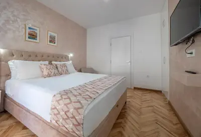 a bedroom with a white bed and a television at Oscar Exclusive Apartment in Budva