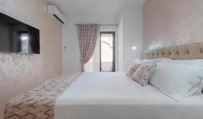 a white bedroom with a large bed with white pillows at Oscar Exclusive Apartment in Budva