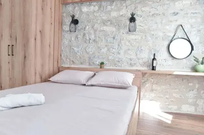 a bed in a room with a stone wall at Sambra old town apartment in Budva