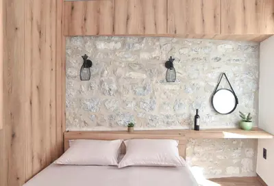 a bedroom with a bed with a stone wall at Sambra old town apartment in Budva