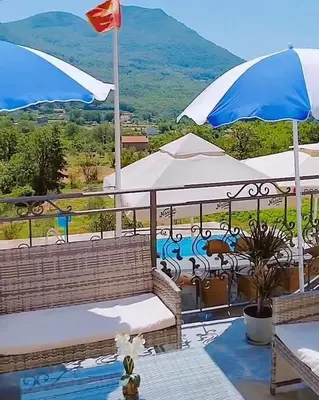 a balcony with benches and umbrellas with a view of a mountain at Apartmani Dumezic in Bar