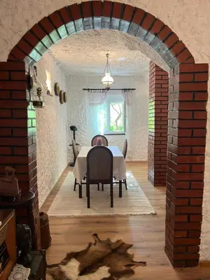 a dining room with a table and a brick wall at Sailor's Rustic House in Virpazar
