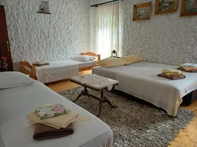a room with three beds and a table in it at Sailor's Rustic House in Virpazar