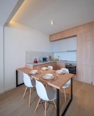 a kitchen with a wooden table and white chairs at Horizon-One bedroom apartment with pool Jane in Becici