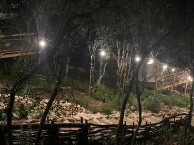 a bridge over a river at night with lights at Bigova Glamping in Kotor