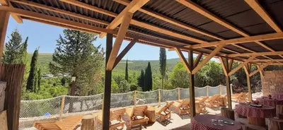 a patio with chairs and tables and a wooden roof at Bigova Glamping in Kotor