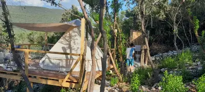 a person standing next to a tent in the woods at Bigova Glamping in Kotor