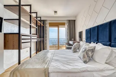 a bedroom with a large white bed with a blue headboard at Quercus Residences Apartments in Sveti Stefan