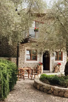 a stone house with a table and benches in front of it at OLIVE QUEEN Rustic Estate in Bar