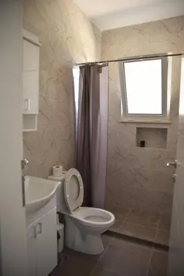 a bathroom with a toilet and a sink and a window at Apartments kupi ul rudaj 41 in Ulcinj
