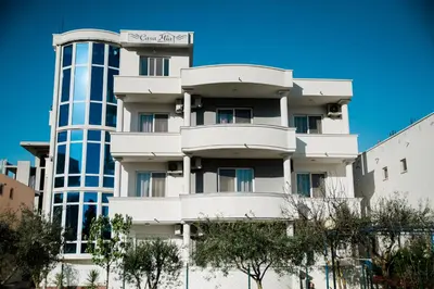 a white apartment building with trees in front of it at Apartments Casa Mia in Ulcinj