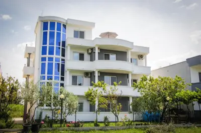 a large white building with blue windows at Apartments Casa Mia in Ulcinj