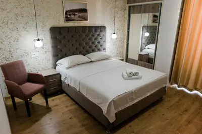 a bedroom with a bed and a chair and a mirror at Apartments Casa Mia in Ulcinj