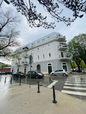 a large white building with cars parked in a parking lot at Apartment DORA in Cetinje