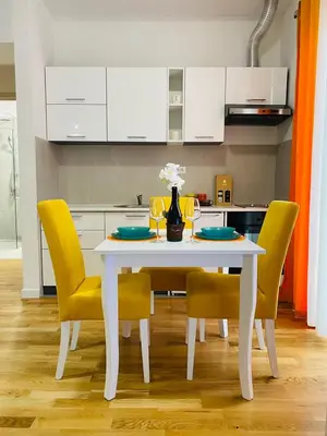 a kitchen with a white table and yellow chairs at Apartment DORA in Cetinje