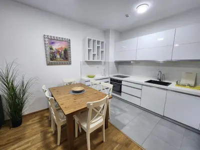 a kitchen with a wooden table and white cabinets at City life in Podgorica
