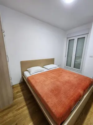 a bedroom with a large bed with a orange blanket at City life in Podgorica