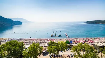 a beach with a bunch of people in the water at Beachfront Hotel Palma - Jaz in Budva