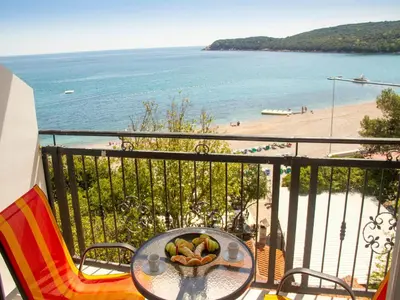 a table with a bowl of fruit on a balcony with a beach at Beachfront Hotel Palma - Jaz in Budva
