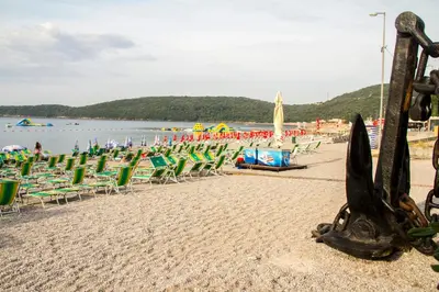 a sandy beach with lawn chairs and umbrellas at Beachfront Hotel Palma - Jaz in Budva