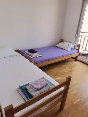 two beds in a small room with a window at Maša Bečići Apartman in Budva