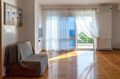 a living room with a chair and a sliding glass door at Royal Villas in Dobra Voda