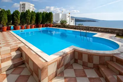 a swimming pool in a resort with the ocean in the background at Royal Villas in Dobra Voda