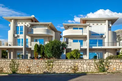 a large white apartment building with a stone wall at Royal Villas in Dobra Voda