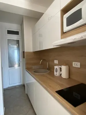 a kitchen with white cabinets and a sink and a microwave at Acacia apartmani Sutomore in Sutomore