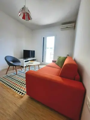 a living room with a red couch and a desk at Acacia apartmani Sutomore in Sutomore