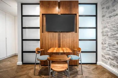 a table and chairs with a television on a wall at Nest Ozana in Kotor
