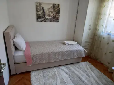 a small bedroom with a bed and a picture on the wall at Stan u maslinama in Podgorica