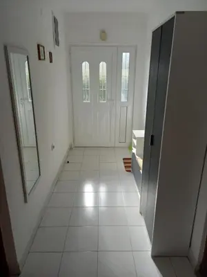 a hallway with a white tiled floor and a door at Stan u maslinama in Podgorica