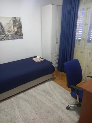 a bedroom with a blue bed and a desk and a chair at Stan u maslinama in Podgorica