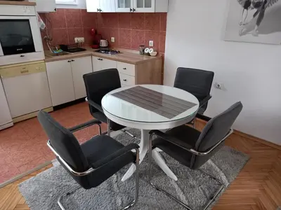 a table and chairs in a kitchen with a table and a counter at Stan u maslinama in Podgorica