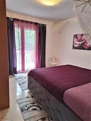 a bedroom with a bed with a red bedspread and a window at Montenegro Smile in Dobra Voda
