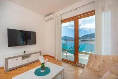 a living room with a couch and a tv and a balcony at Alex Lux sea view apartment 1 in Rafailovici