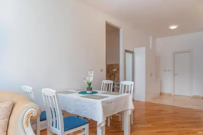 a dining room with a white table and chairs at Alex Lux sea view apartment 1 in Rafailovici