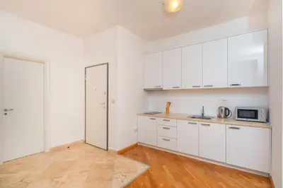 a kitchen with white cabinets and a wooden floor at Alex Lux sea view apartment 1 in Rafailovici
