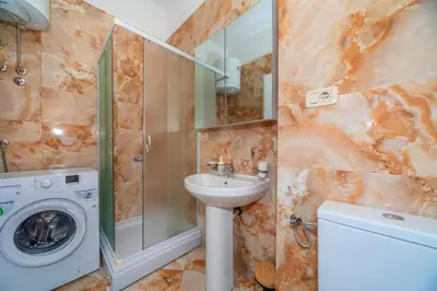 a bathroom with a sink and a washing machine at Alex Lux sea view apartment 1 in Rafailovici