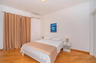 a white bedroom with a bed and a window at Alex Lux sea view apartment 1 in Rafailovici