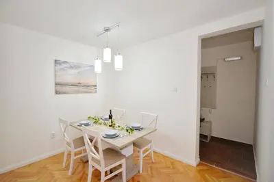 a white dining room with a table and chairs at Unico apartman in Kotor