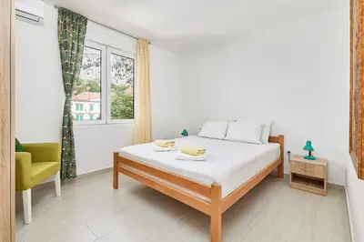 a bedroom with a bed and a chair and a window at Apartment Pavle in Kotor