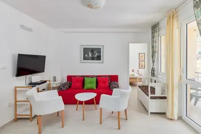 a living room with a red couch and white chairs at Apartment Pavle in Kotor