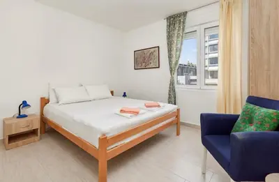 a bedroom with a bed and a blue chair at Apartment Pavle in Kotor