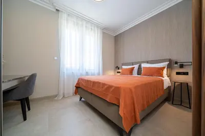 a bedroom with a bed with an orange blanket and a desk at C Group apartments in Kotor
