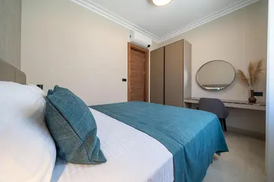 a bedroom with a bed with a blue blanket and a mirror at C Group apartments in Kotor